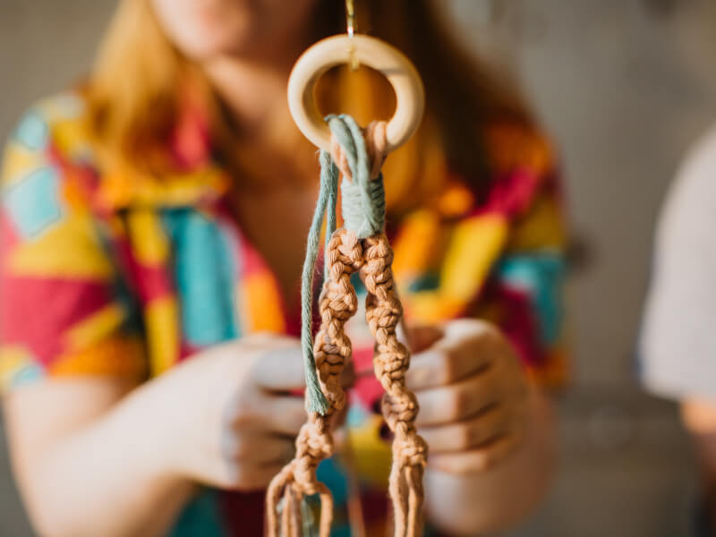 Close-up of a macrame hanger with a woman in background